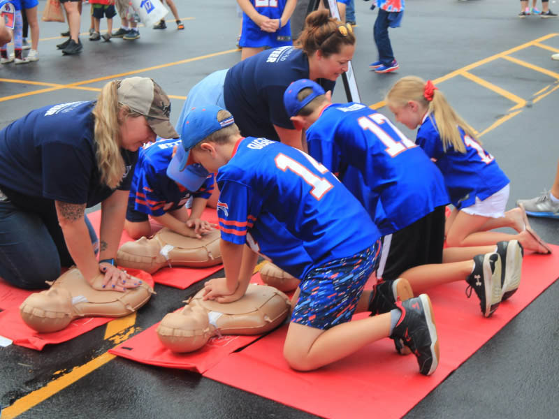 Voluntarios ayudan a los niños aprender RCP durante el campamento de entrenamiento de los Bills de Buffalo en Rochester Nueva York en agosto de 2023. (Foto cortesía de Alik Matthews)