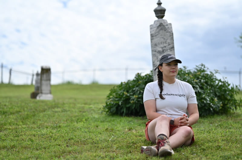 Olivia Brien, the tribe's director of communications, sits in front of the headstone for Louisa Brien, her third great-grandmother. (Photo by Walter Johnson Jr./American Heart Association)