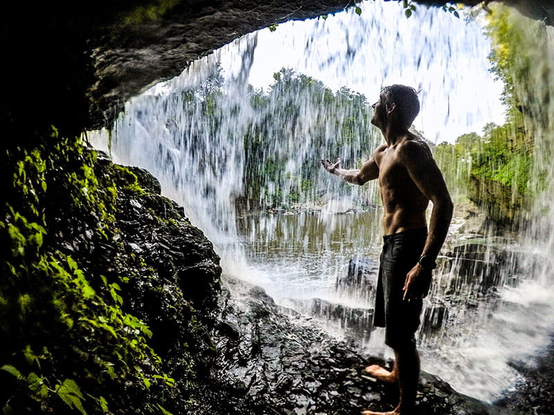 Nick Troutman standing under a waterfall at Upper Ball's Falls in Ontario, Canada