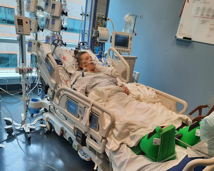 Sara Adair in a hospital bed connected to machines