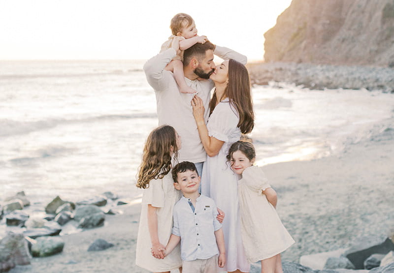 Molly Carlton sits on the shoulders of her dad, Tom, while surrounded by her mom, Melissa, and siblings Lily, Harry and Abi, on a beach in 2022