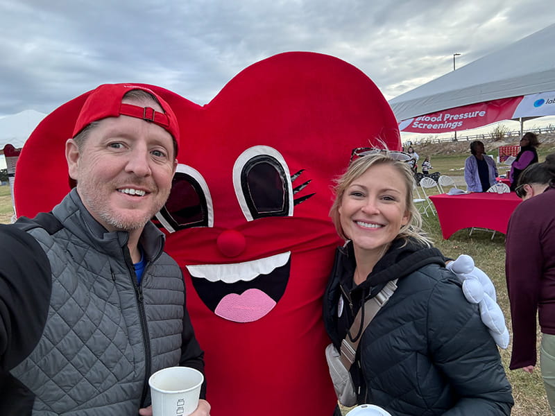 Kyle Hartley and Alex Stolle with a Heart Walk mascot at the American Heart Association Heart Walk in Hampton, Virginia, in November 2024