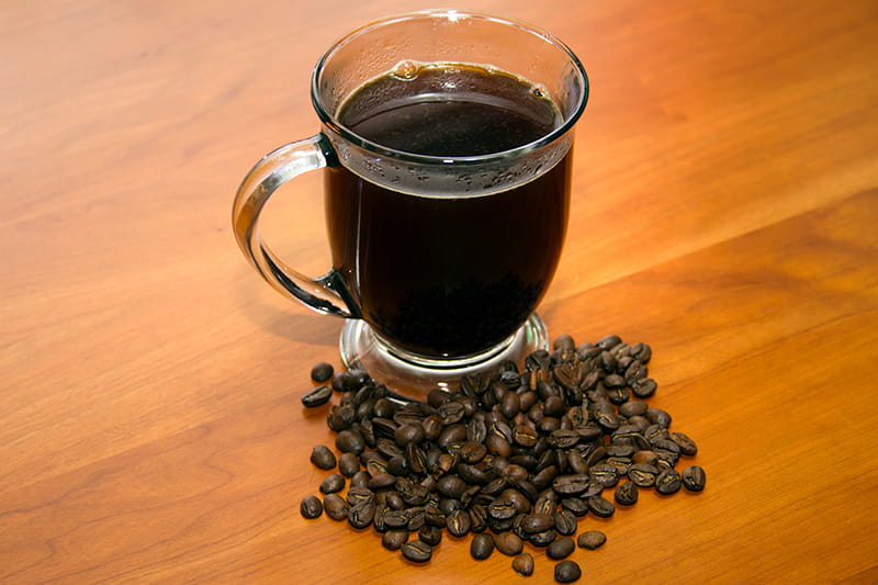 a mug of coffee on a table next to a pile of coffee beans