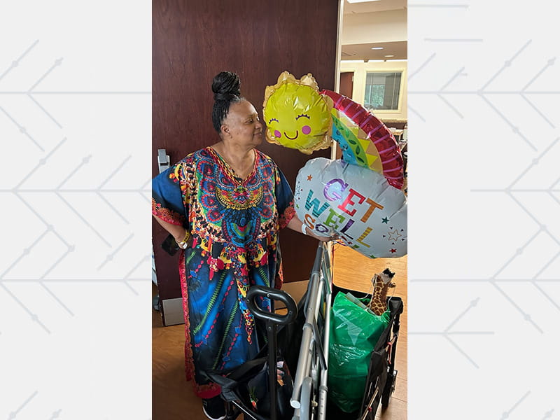 Elizabeth standing beside her “Get Well Soon” balloons.