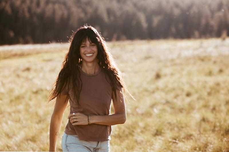 Claudia Davis DiDomenico smiling and walking through a field in the sunshine