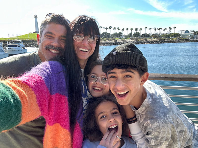 Claudia Davis DiDomenico with husband Tarik and their children Alaia, Bela and Kai outside at a sunny waterscape
