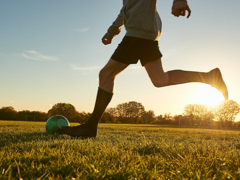 Young 15-year-old male football player training on a field during practice.