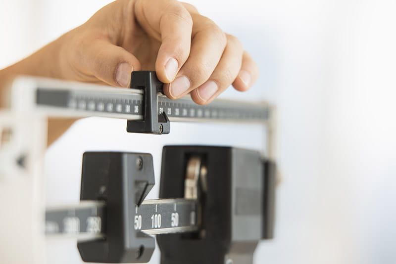 Hands adjusting a medical scale.