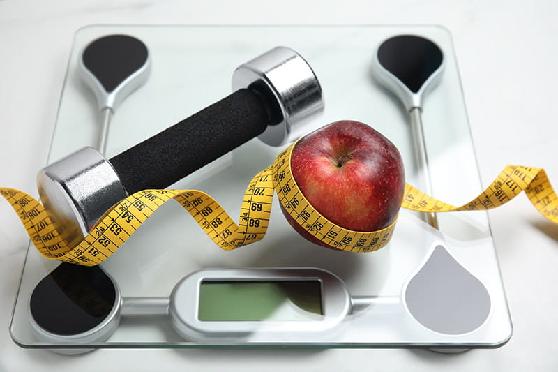 Apple, measuring tape, and scale.