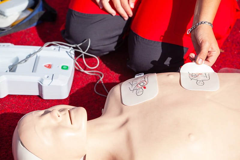 A volunteer working with an AED and a CPR manikin