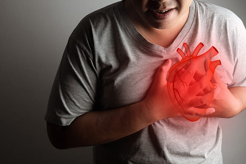a man holding his chest in pain, with an illustration of an anatomical heart drawn over his chest