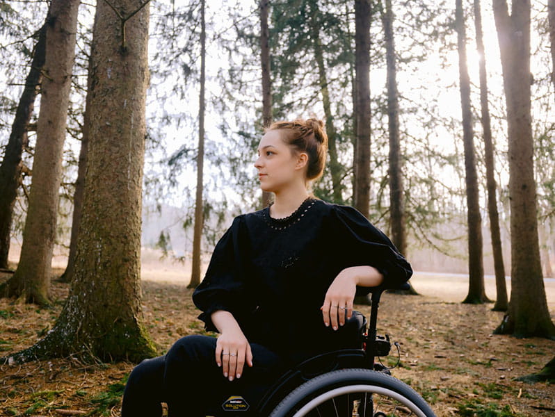 Caroline Laubach posing in her wheelchair among tall trees