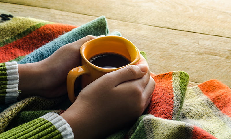 close up of hands holding a full mug of coffee