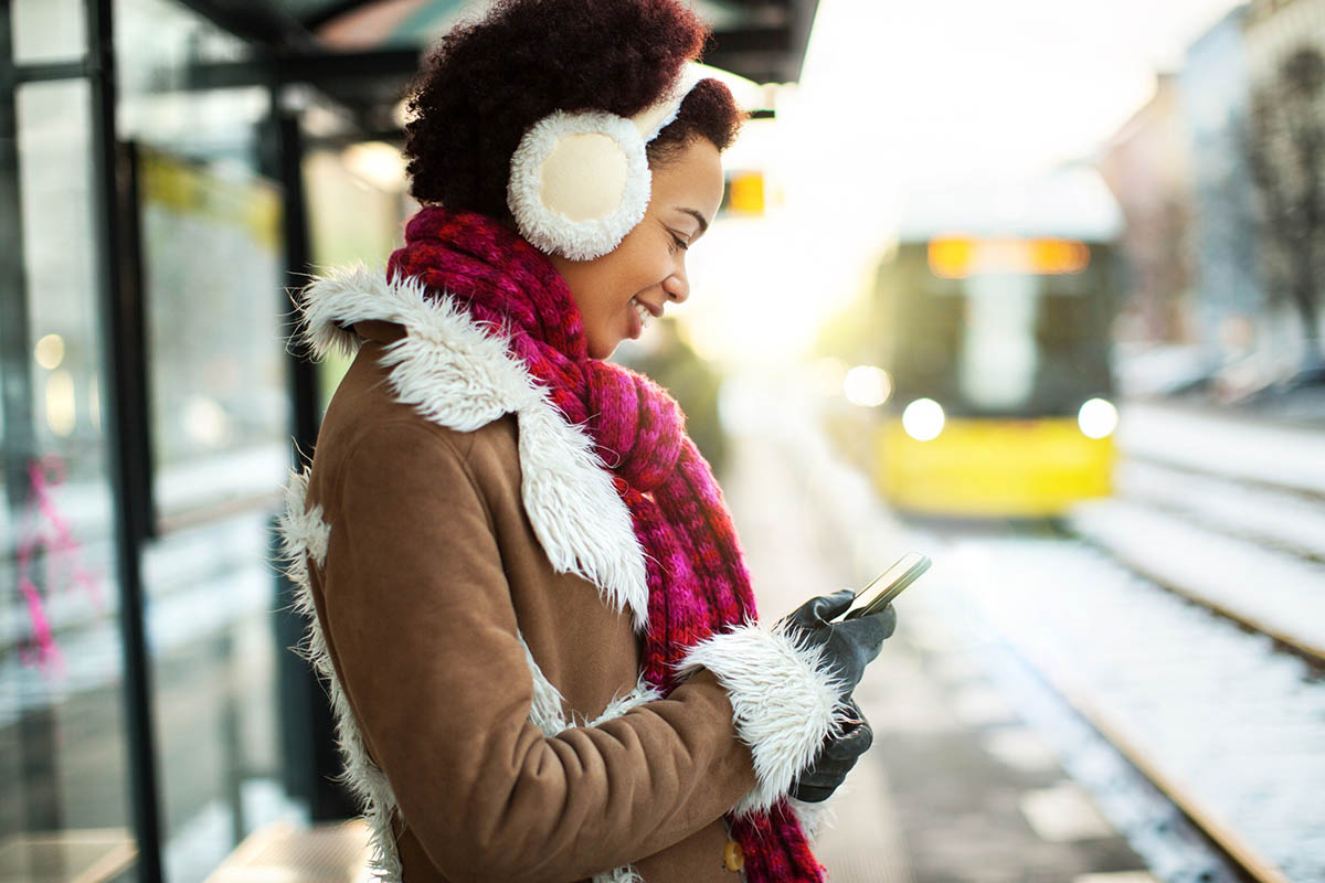 Young Black woman reading her phone on a train platform (alvarez/E+, Getty Images)