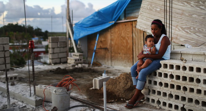A mother holds her 9-month-old baby three months after Hurricane Maria destroyed their home in Puerto Rico