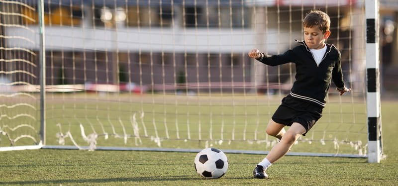 Boy in goal kicking soccer ball