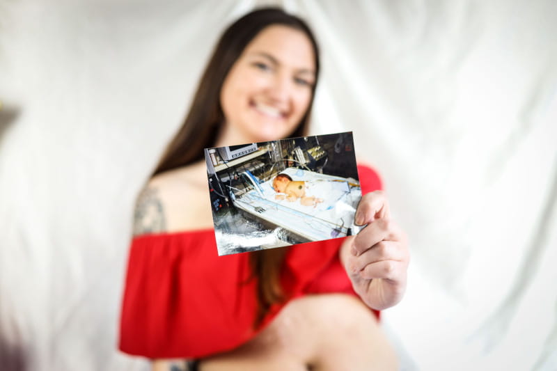 Micky Foos holding a picture of herself as a baby. (Photo courtesy of Paytience Rose Photography)