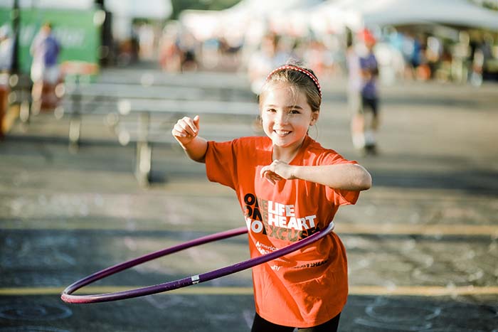 Little girl hula hooping at Heart Walk event