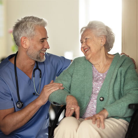 Home care staff smiling with elderly woman in wheel chair