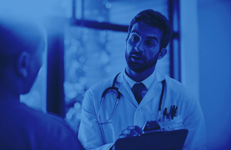 doctor with clipboard speaking to patient