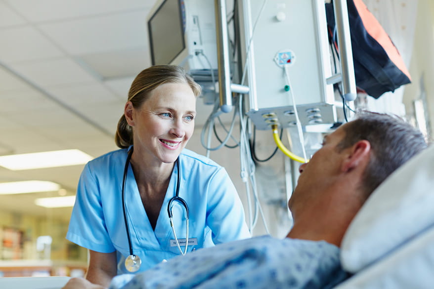 Healthcare professional smiles while caring for patient in hospital bed