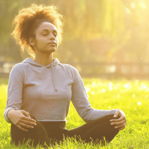 woman sitting on grass doing yoga