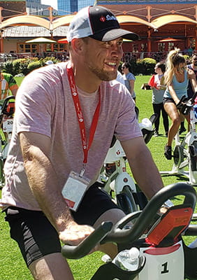 Jeffery Marquis riding a stationary bike at an outdoor event