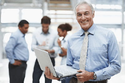 man in business office environment holding laptop