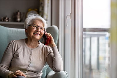 older woman sitting in chair at home talking on the phone