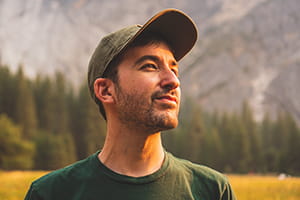 individual trustee: a man in a baseball cap looking to the side, up into the sunshine, outdoors