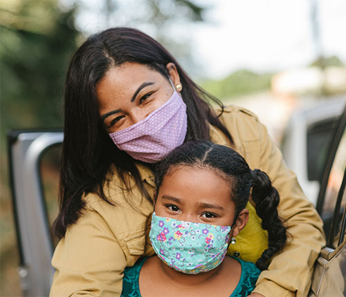 Mother and child masked standing by car