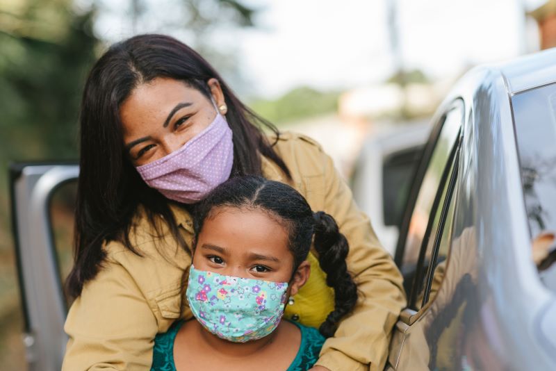 Mother and child masked standing by car