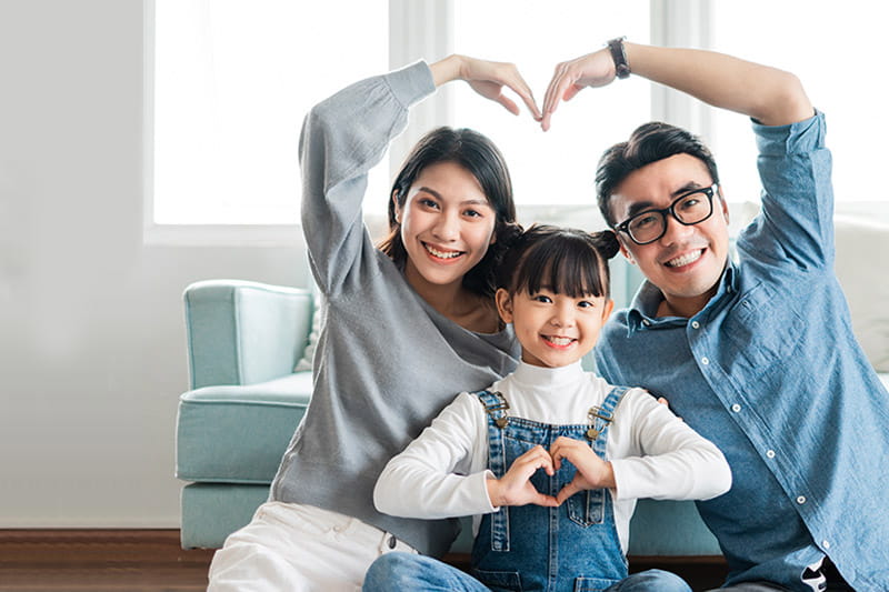 small Asian family portrait at home forming hearts with their hands and arms