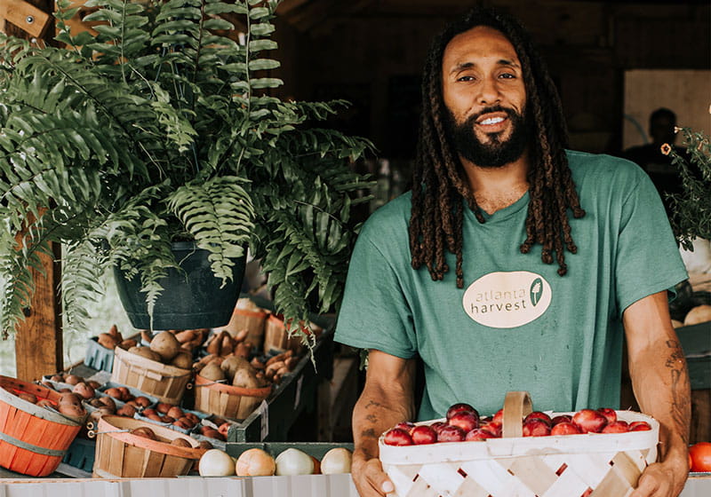 A man with Atlanta Harvest holding a basket of produce