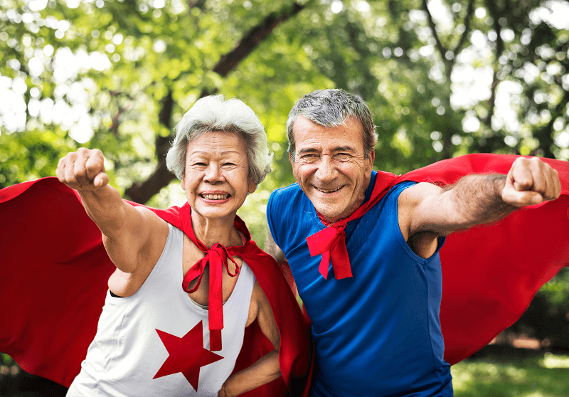 two seniors in super hero capes