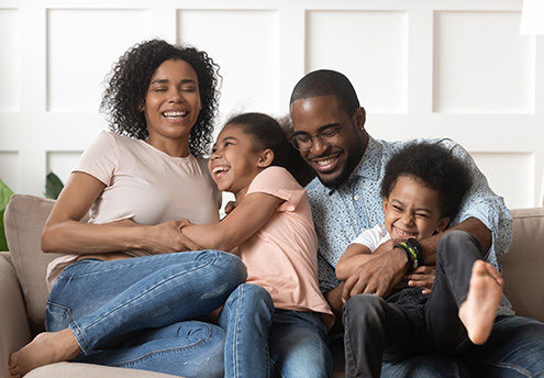 Family laughing and sitting on a sofa