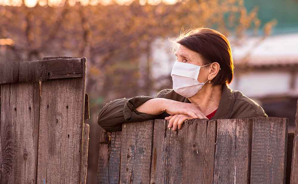 woman wearing protective face mask while looking over fence