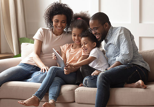 family sitting on sofa looking at ipad