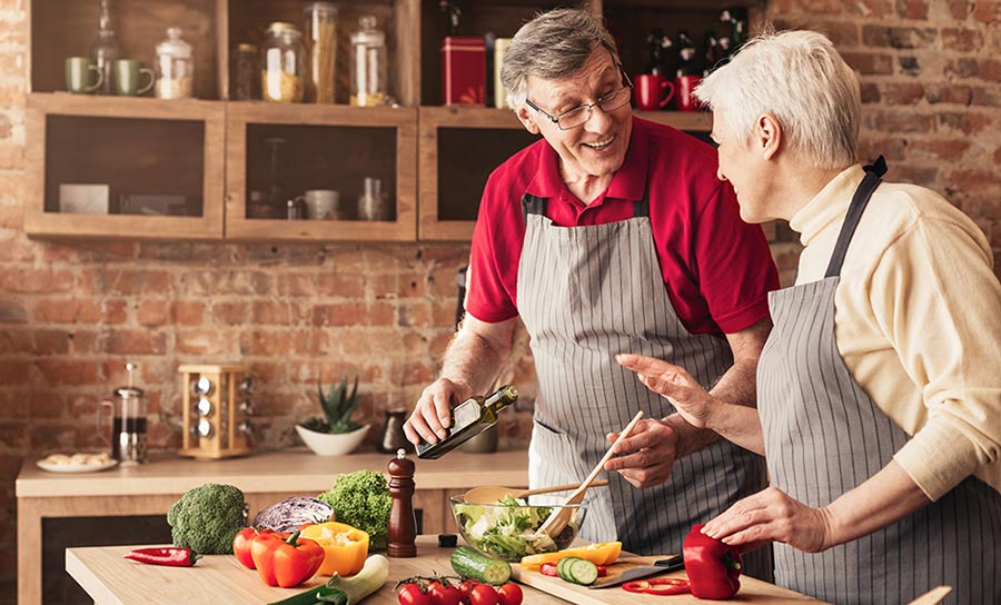 man and woman in kitchen making salad