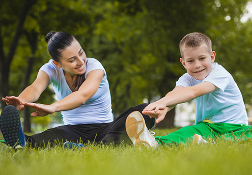 mother and son stretching outdoors in grass mother and son stretching outdoors in grass
