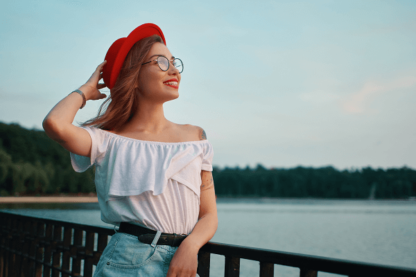 portrait of positive girl with irresistible smile leaning on a rail by a lake