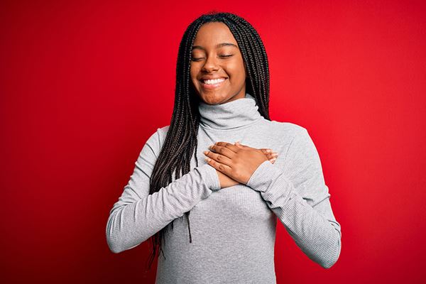 happy young woman holds hands over heart happy young woman holds hands over heart