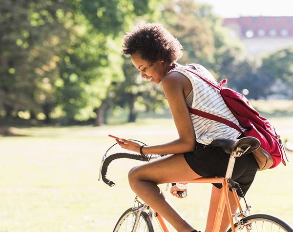 young woman on bicycle reading phone young woman on bicycle reading phone