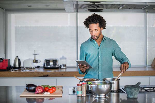 young man reading recipe from tablet while cooking young man reading recipe from tablet while cooking