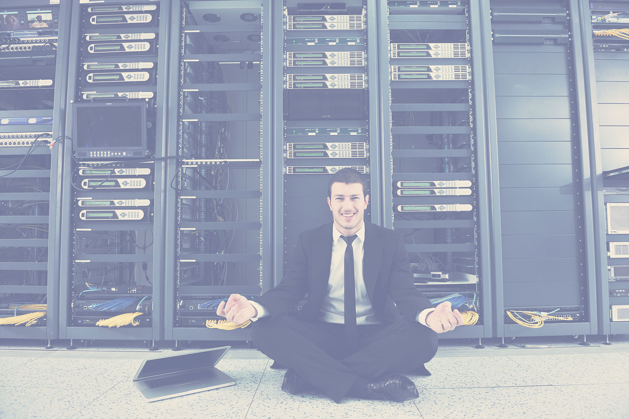 Businessman doing yoga next to computer servers