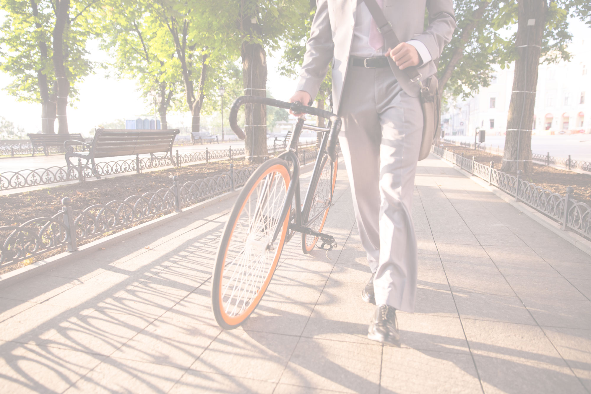 Businessman walking with bike through city park