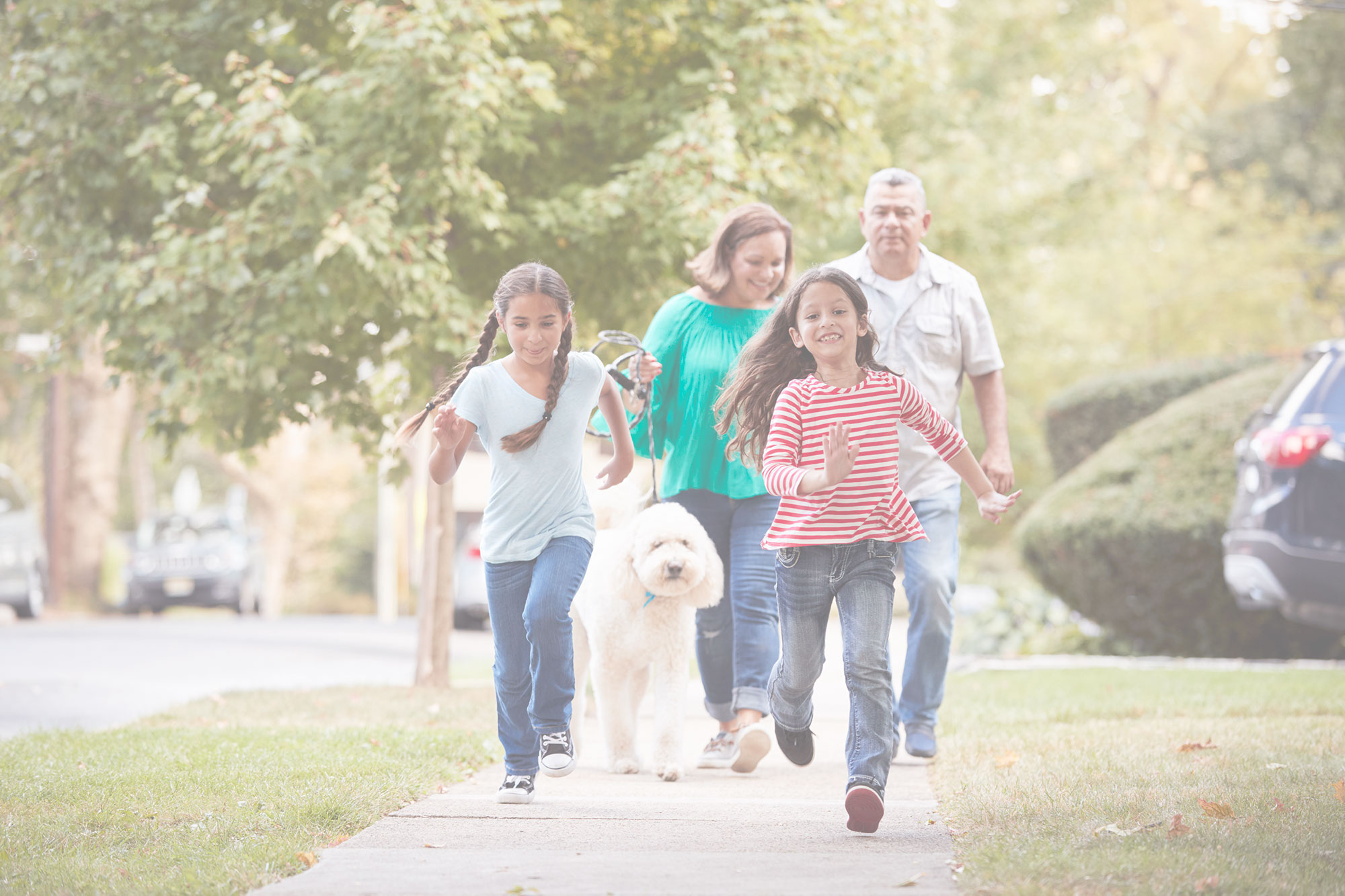 Grandparents walking the dog with their granddaughters on a sidewalk