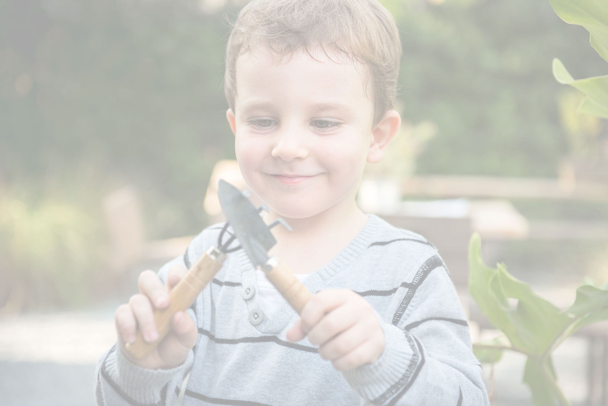 Young boy playing with garden tools