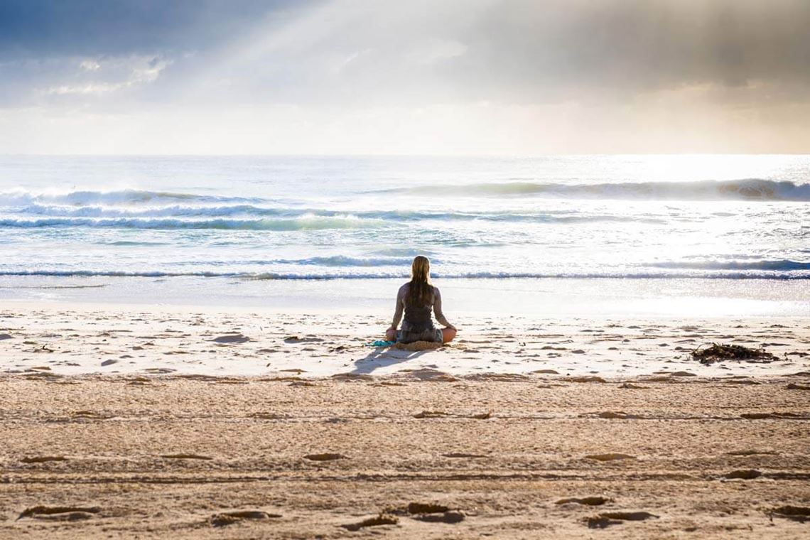 person sitting on a beach by the water