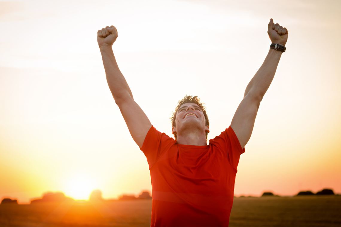 man raising his arms up in victory